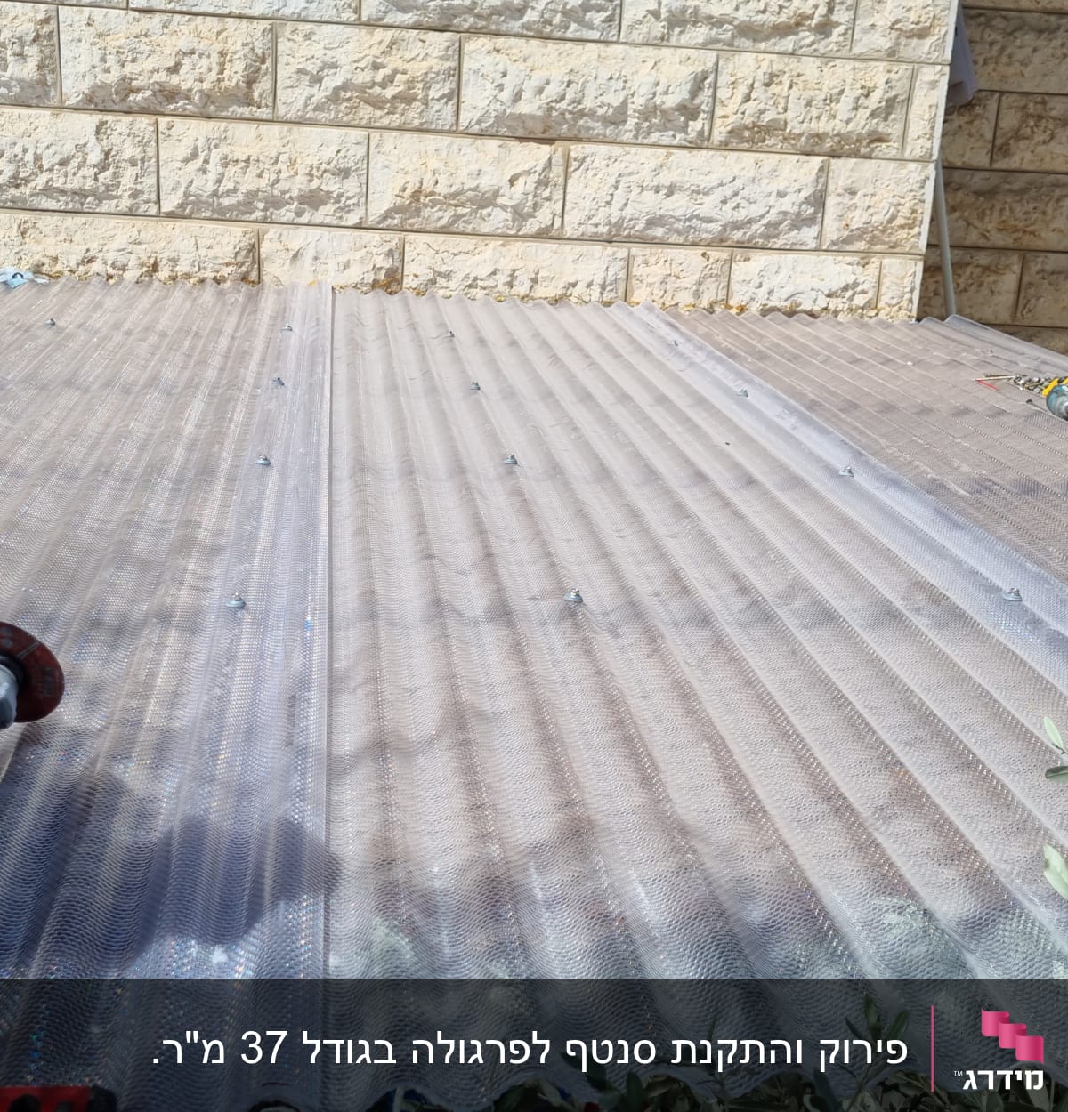 כלי עבודה על גג פלסטיק שקוף ליד קיר אבן